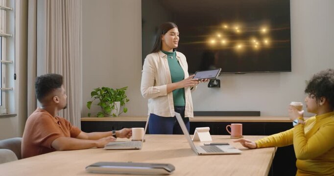 African American colleagues in boardroom following leader in green top tapping tablet showing plan