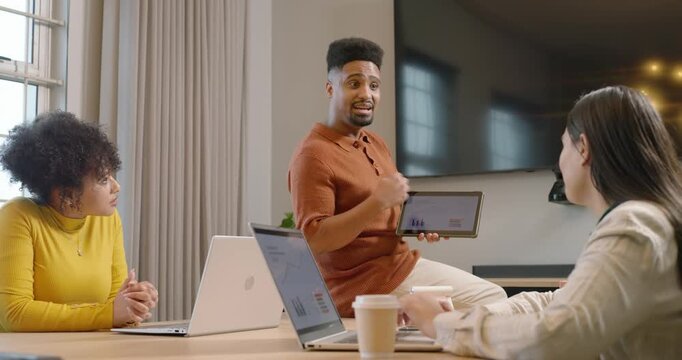 African American team watching man entering, turning tablet showing charts while others typing