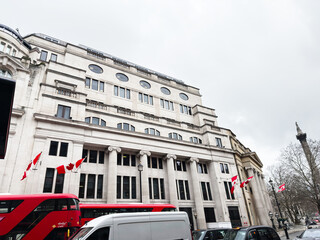 Fototapeta premium Historic stone office Oceanic House building with Canadian flags and red buses on a London, UK Cockspur street