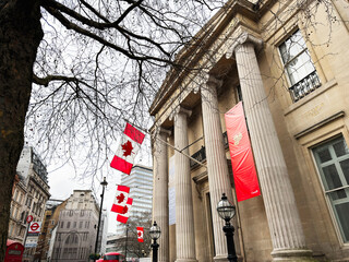 Fototapeta premium Canadian flags fluttering outside a classical building on Cockspur Street in London, UK, near Trafalgar Square