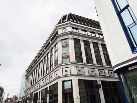 Historic department store building with clock tower and modern shops on a London, UK Panton street