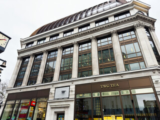 Fototapeta premium Historic commercial building with TWG Tea and LEGO storefronts and classical columns in London, UK