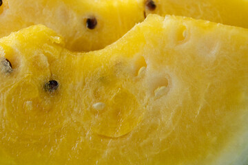 Macro close-up of ripe yellow watermelon wedges showing juicy golden flesh, dark seeds and pale green rind, creating a vibrant summer food background. © Jolanta