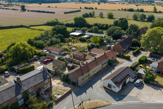 Aerial photo overlooking traditional stone houses and rural homes in Thirsk Yorkshire surrounded by farmland fields gardens mature trees country lanes and peaceful North Yorkshire countryside