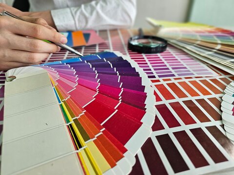 Person selecting color samples for a design project in an indoor setting with fabric swatches and paint chips