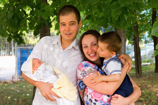Family portrait of husband, wife, 1 year old kid and newborn baby boy shot outdoors