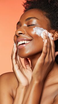 Joyful woman applies rich moisturizer, highlighting hydrated glowing skin in soft daylight. Peach background and modern beauty aesthetic emphasize skincare and self-care.