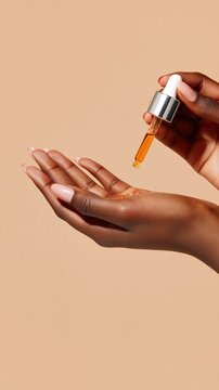 A close-up of a hand with a cosmetic dropper releasing amber serum onto the palm. Luminous highlights and creamy beige backdrop evoke premium skincare hydration and glow.