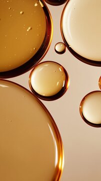 Close-up macro of luminous oil droplets floating in translucent liquid. Warm honey and creamy beige tones create an abstract, minimal skincare editorial scene.