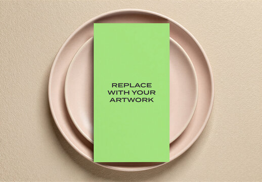 Vertical brochure mockup with a placeholder card on stacked ceramic plates, minimalist stationery presentation textured surface, flat lay overhead view, graphic design template for print media