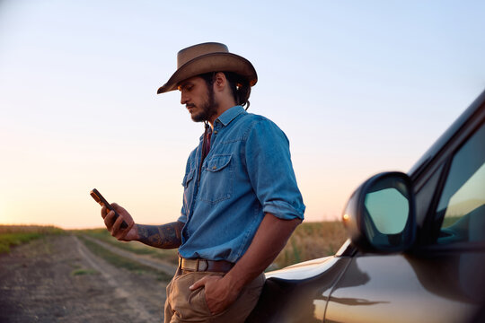 Farm owner using mobile phone while standing by his truck in field.