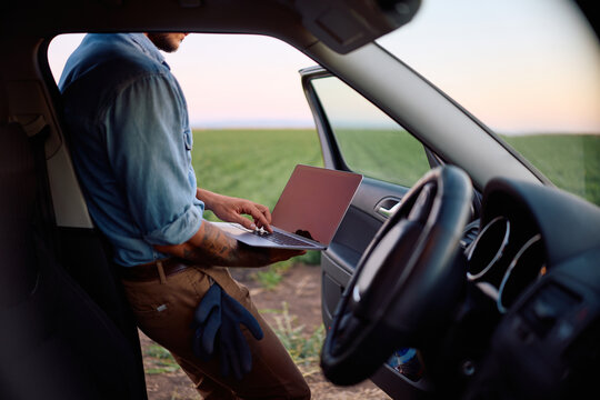 Unrecognizable agricultural field worker working on laptop.