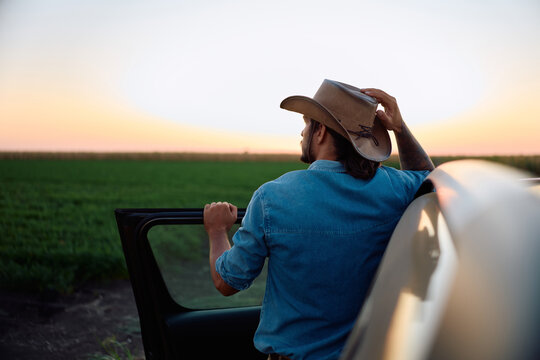 Rear view of agricultural worker looking at his farmland while standing by truck.