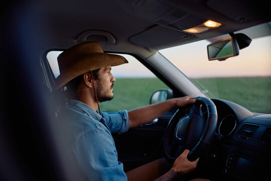 Young farmer driving truck through agricultural field.