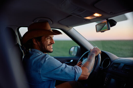Happy farm worker driving pickup truck in field.