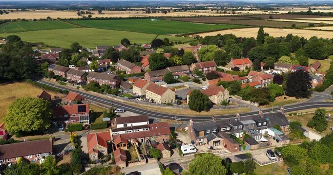 Aerial footage overlooking traditional homes near Thirsk Yorkshire with country roads mature trees and extensive agricultural fields creating a scenic view across the North Yorkshire countryside