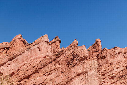Red sandstone cliffs and towering rock formations dominate the desert landscape of quebrada de las conchas in cafayate. Argentina. Cloudless blue sky