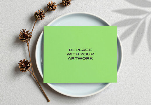 Rectangular card mockup on a light blue ceramic plate with pinecones and plant shadow, flat lay composition, stationery branding presentation, graphic design template