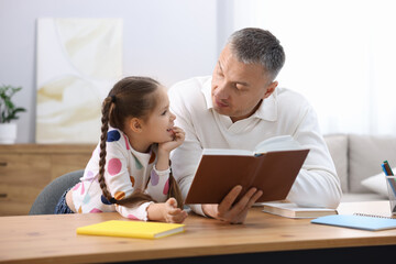 Fototapeta premium Father helping his daughter with homework at wooden table indoors