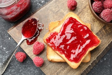 Raspberry jam, toasts and fresh berries on black table, flat lay © New Africa