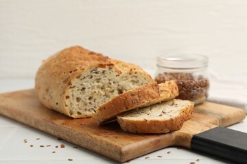 Naklejka premium Fresh bread with flax seeds on white table, closeup