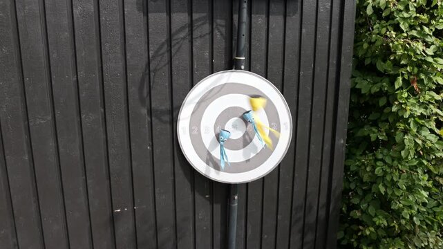 Close-up view of four toy squids hitting numbered dartboard while fifth falls outdoors. Sweden.