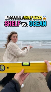 Shelf hack level impossible: holding white shelf against ocean waves at beach