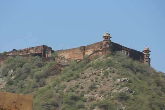 Ancient historic Jaigarh Fort brick defensive walls and watchtower chhatris on a hilltop against a blue sky in Jaipur.