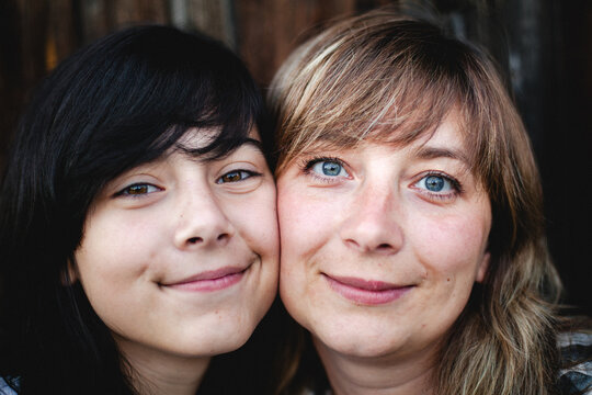 Close up portrait of a smiling teenage girl and woman looking at the camera together