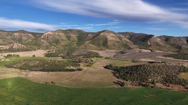 Aerial of high desert mountains in Mancos Colorado with scrub brush and farmland with dry rolling hills in summer