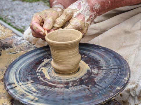Potter Shaping Clay on a Spinning Pottery Wheel With Muddy Hands
