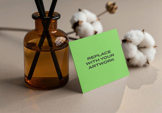Business card mockup displayed on a textured surface with an amber glass diffuser and cotton stems, realistic stationery branding presentation for graphic design, print, Template