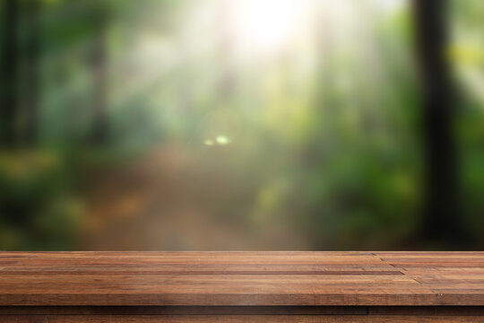 Green background with wooden table. Wooden table in the foreground with a lush, green park scene in the background. Beautiful natural summer background with empty wooden table in nature outdoor.