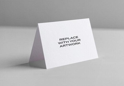 Folded card mockup standing upright on a light gray surface, minimalist stationery presentation with text placeholder, clean design template for branding or print
