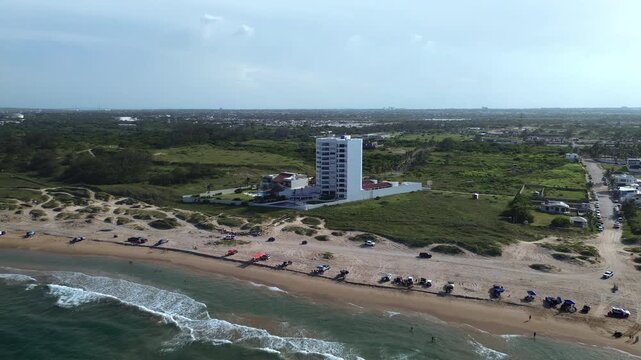 Miramar Beach coastline with calm Gulf waters, sandy shore, local visitors, parked vehicles and natural green landscape