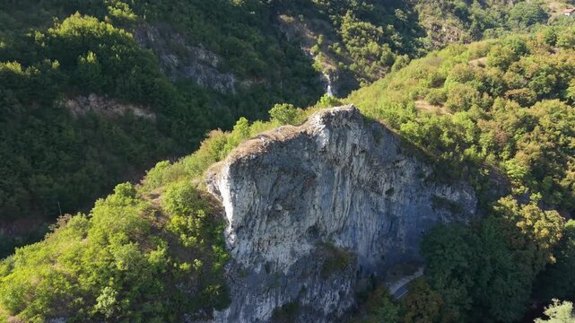 Aerial Flyover of Rock Wall with Fleur-de-Lis Flag Above Dariva Revealing Expressway and Moving Car, Sarajevo, Bosnia and Herzegovina