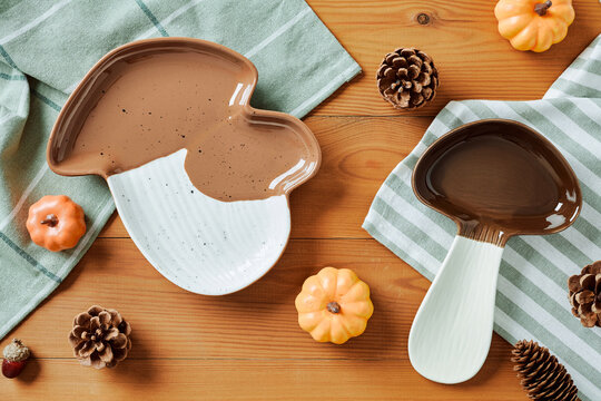 Mushroom shaped ceramic plate with autumn decor on wood background.