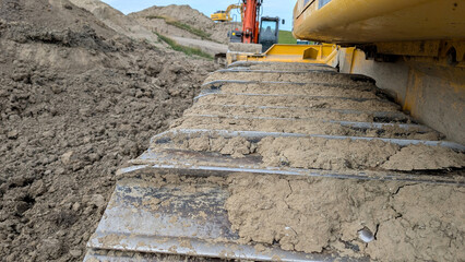 Close-up of a dirty metal excavator track at a construction site.  © Inha