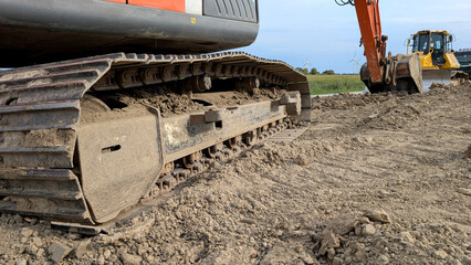 Close-up of a steel crawler track on a tracked excavator at a construction site.  © Inha