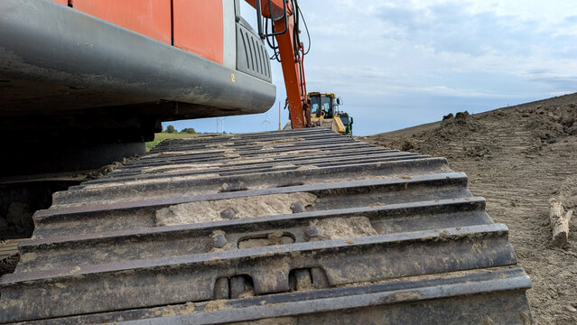 Close-up of a steel crawler track on a tracked excavator at a construction site. 