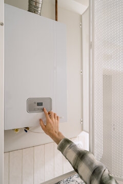 A person adjusts the settings on a gas boiler at home