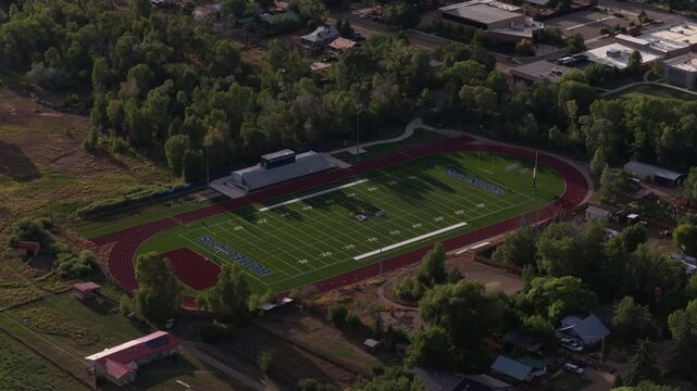 Aerial of high school athletic stadium football field and track in Mancos Colorado small rural town in summer