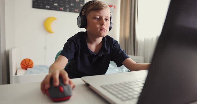 Boy with headphones using laptop at home in his room. Gaming, music listening or browsing internet