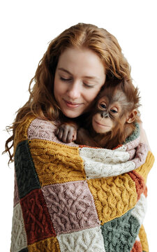 Portrait of a smiling woman with long curly red hair hugging and holding a baby orangutan wrapped in a colorful