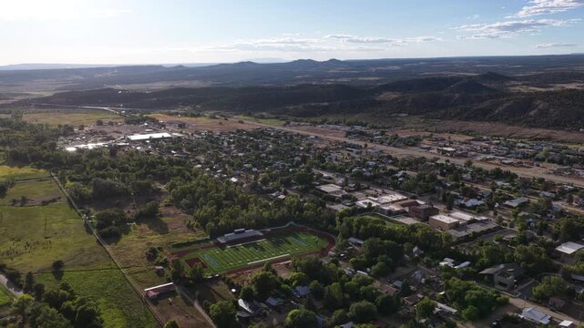 Wide aerial of Mancos Colorado small rural town in high desert with sports fields and rolling hills