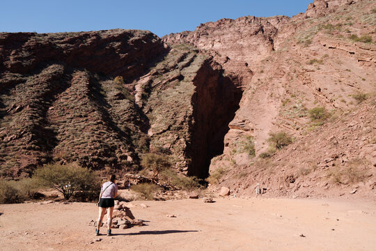 Woman hiking in the garganta del diablo canyon, a natural geological formation with impressive red rock walls and arid vegetation in cafayate, salta, argentina