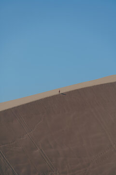 Lone Man Climbing a Giant Sand Dune in the Ica Desert of Peru Surrounded by Vast Arid Landscapes