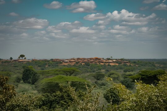 Wide aerial view of a remote rural village nestled in green forest under