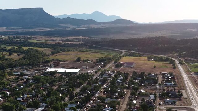 Aerial of CO 184 North Main Street commercial corridor in Mancos Colorado in summer with surrounding mesas and mountains