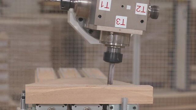 CNC woodworking machine with multi spindle revolver milling head processing wooden detail close up.  Automated CNC woodworking and shaping of wood components. Wooden furniture factory and manufacture.